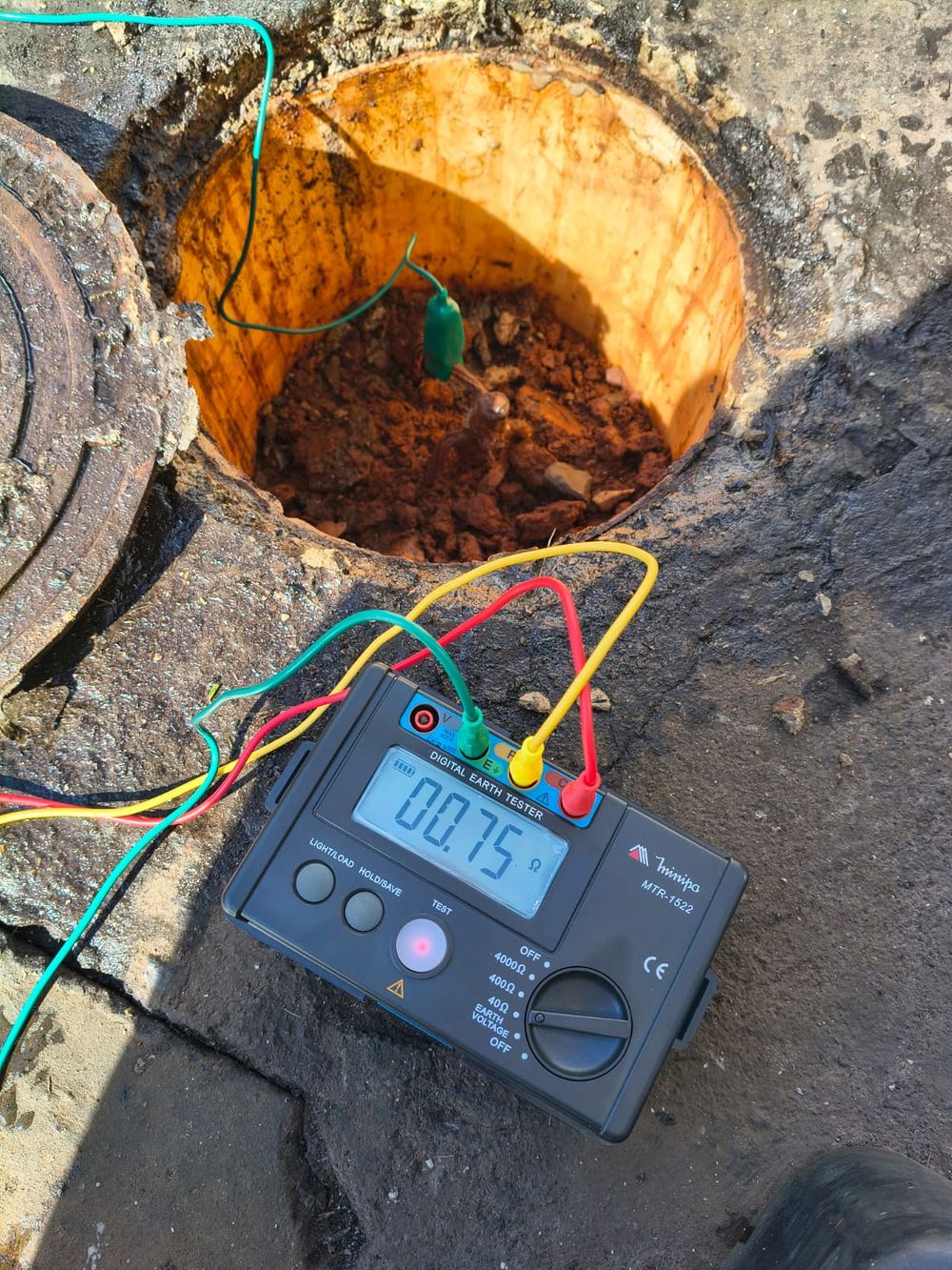 Terrômetro Minipa MTR-1522 marcando 0,75 ohm, conectado ao eletrodo dentro da caixa de inspeção de aterramento
