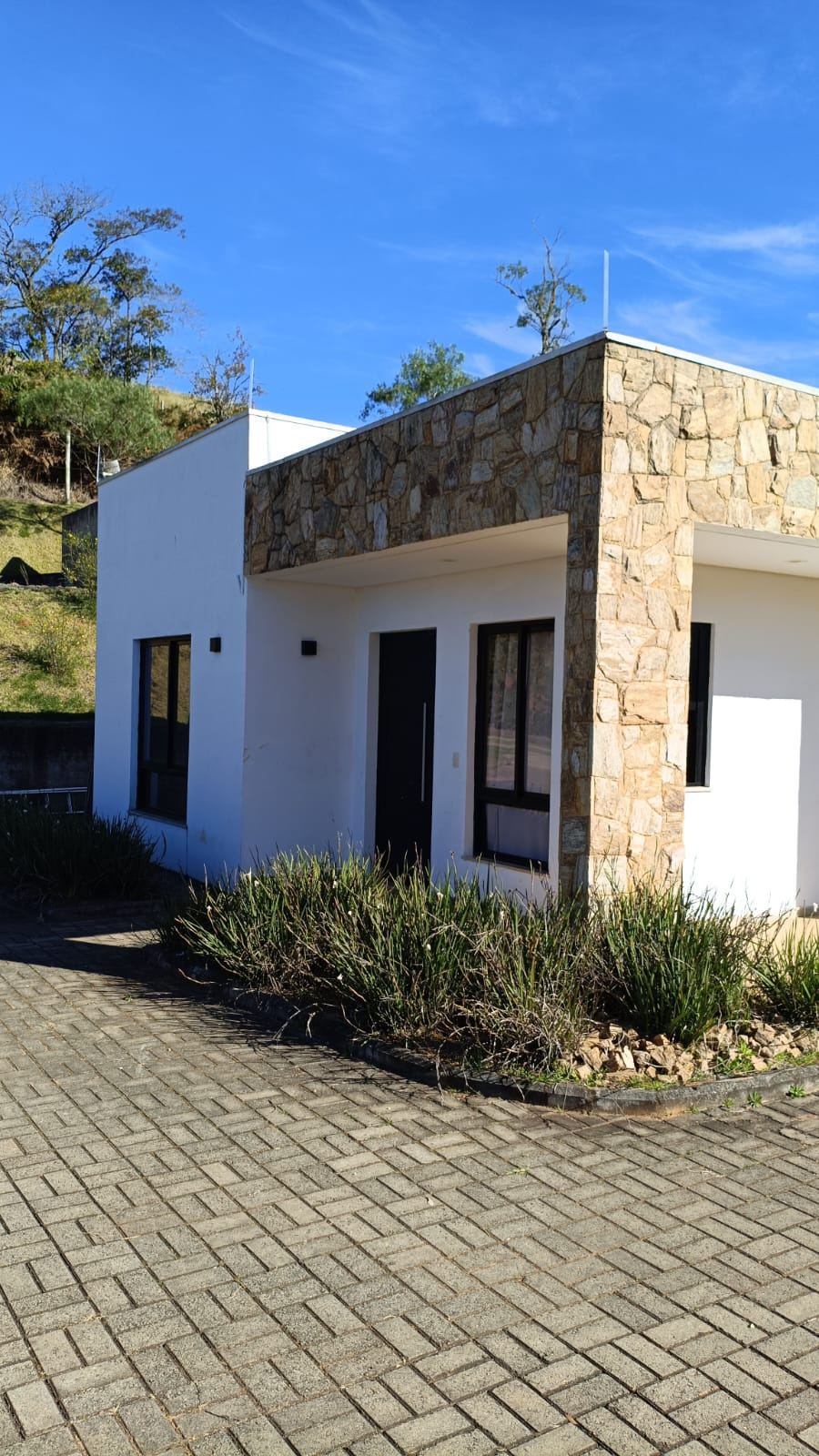 Residência de pedra em sítio com descida de para-raios instalada de forma discreta na fachada